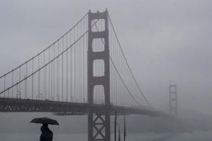 Pedestrians stand under an umbrella in front of the Golden Gate Bridge in San Francisco on January 11.