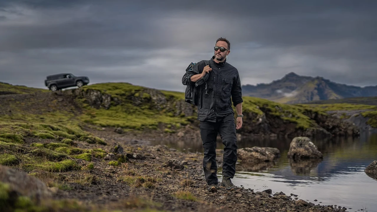 Walker on a mountain range wearing rugged outdoor clothing next to a lake